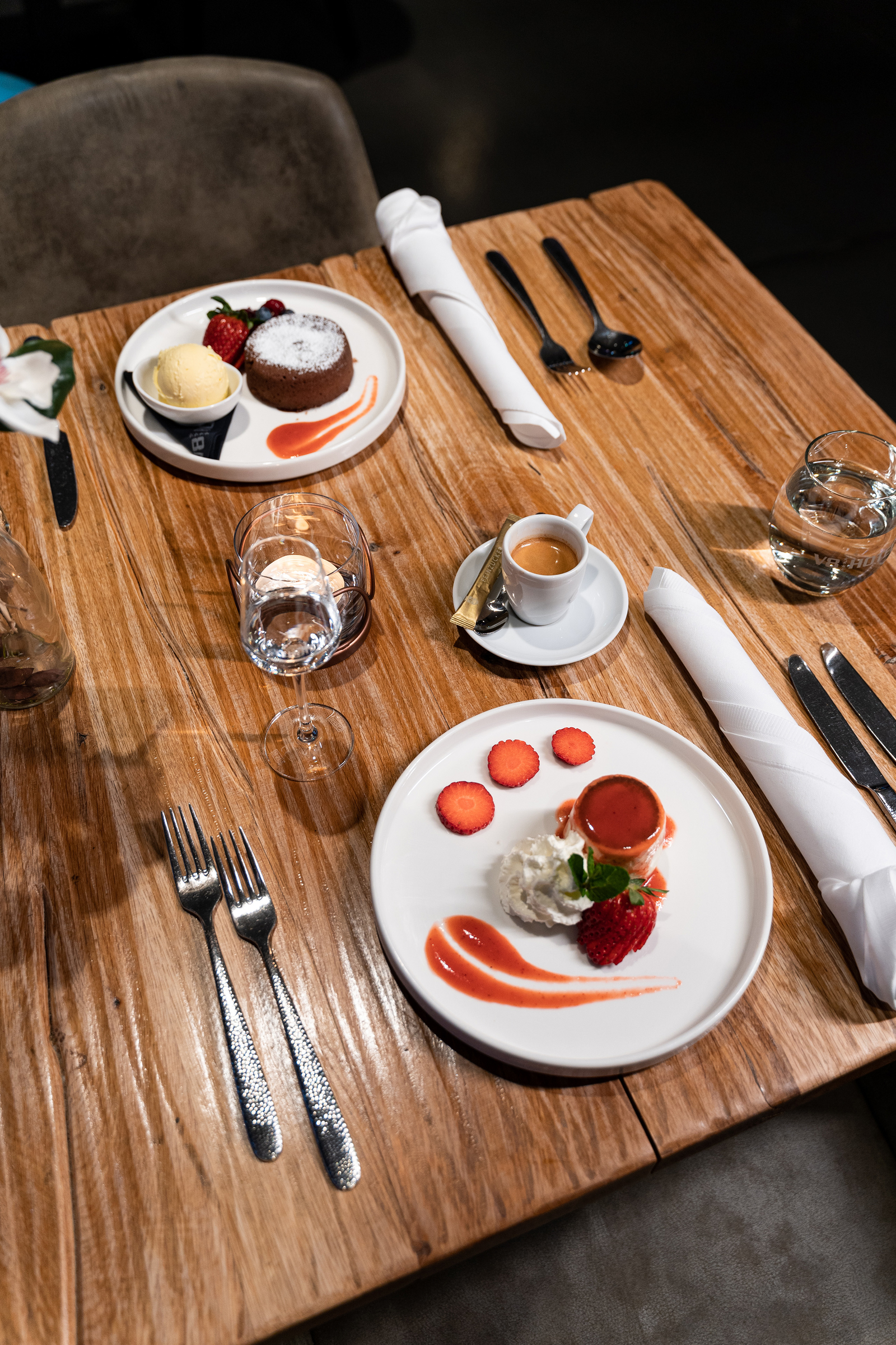 Blick von oben auf einen gedeckten Tisch mit zwei süßen Nachspeisen sowie Wasser und Espresso im Restaurant Böblingen.