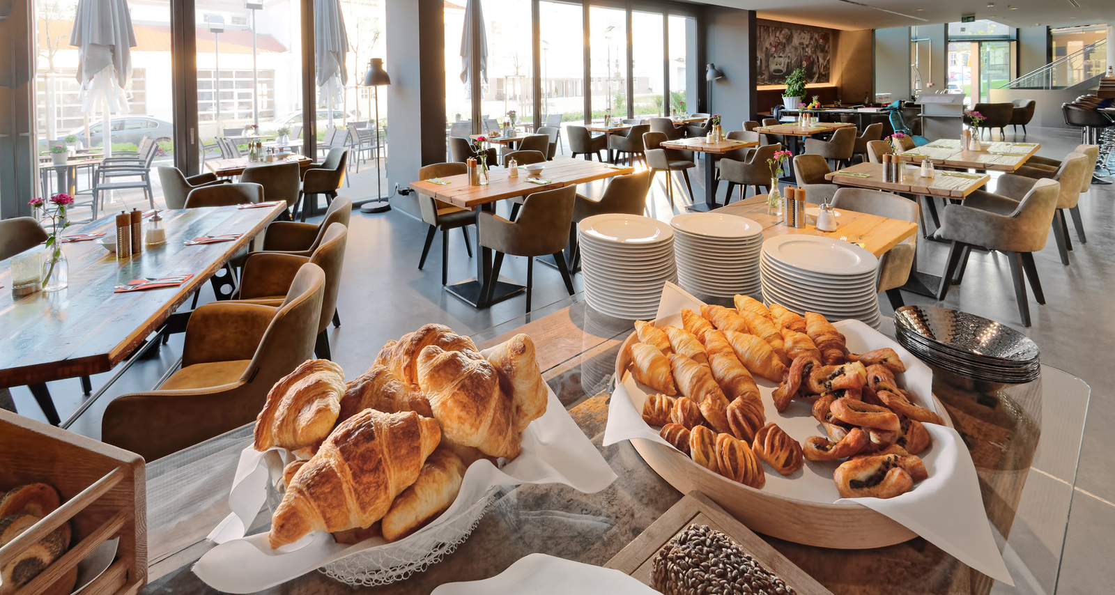 Blick vom Buffet mit leckeren Croissants und weiteren süßen Backwaren auf die Tische im hellen Restaurant Böblingen.