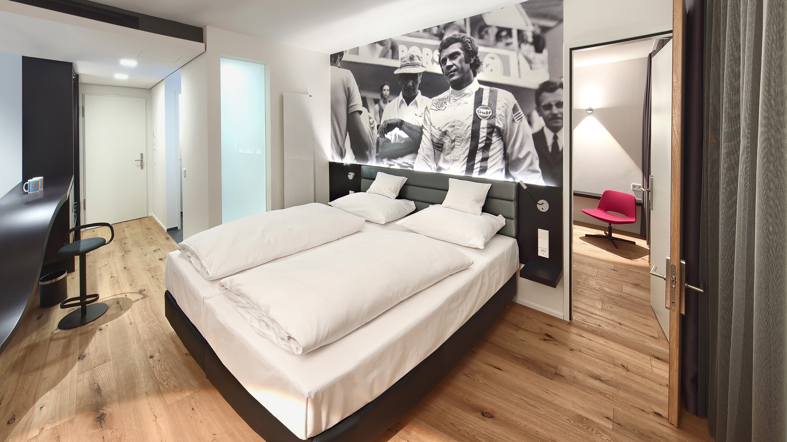 Zwei Einzelbetten unter einem schwarz-weiß Bild eines alten Rennautos im Familienhotel Stuttgart.