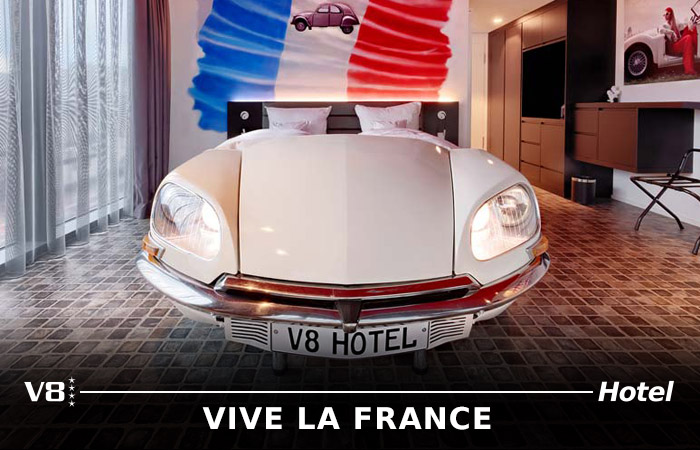 Vive La France Zimmer mit weißem Sportwagenbett und Frankreichtapete im Themenhotel Stuttgart.