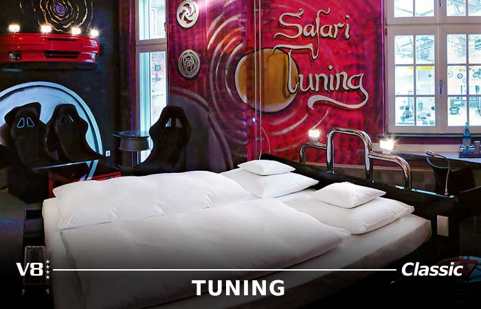 Safari Tuning Themenzimmer mit Doppelbett, Sitzmöglichkeit und bunter Tapete im Hotel in Böblingen.
