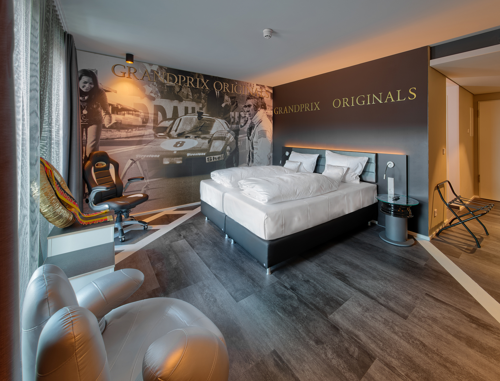 Großzügiges Doppelbett mit leuchtendem Kopfteil im Themenzimmer mit Grandprix-Motivtapete im V8 Hotel