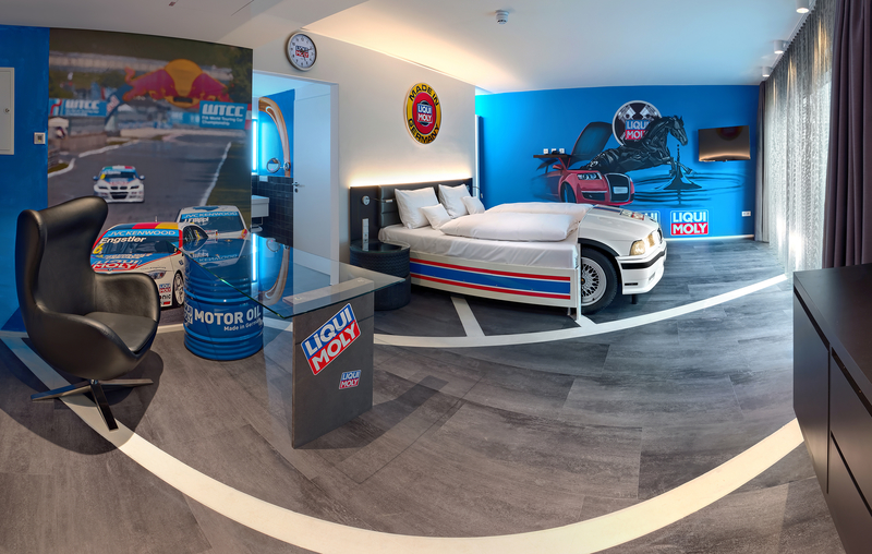 Liqui Moly Themenzimmer im V8 Hotel mit Autobett, Glasschreibtisch und Motivtapeten, die Autorennen zeigen