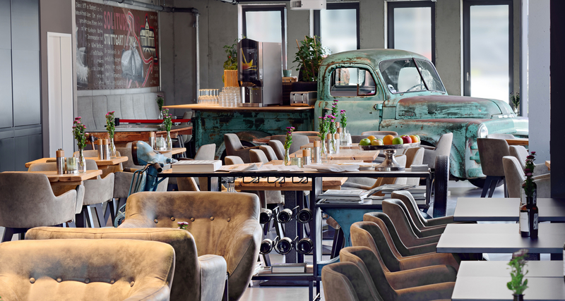 PICK-UP Restaurant mit langer, gedeckter Tafel und altem, verrosteten Pick-Up im Hintergrund.
