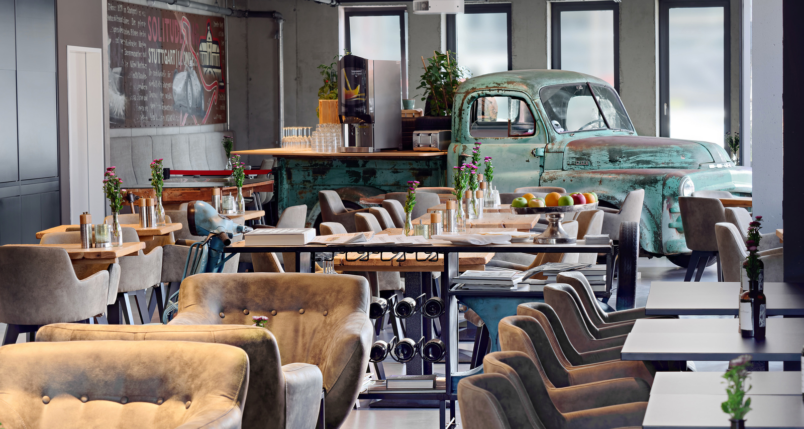 PICK-UP Restaurant mit langer, gedeckter Tafel und altem, verrosteten Pick-Up im Hintergrund.