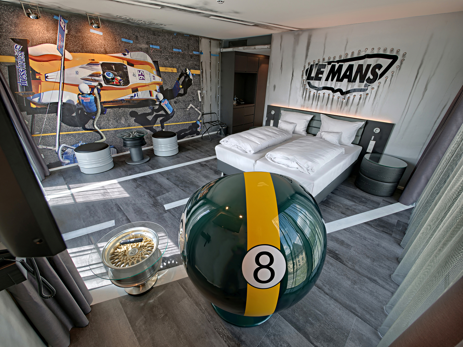 Autozimmer Le Mans mit Motivtape, die ein Rennauto zeigt, gegenüber eines grünen Sessels und eines Doppelbetts.