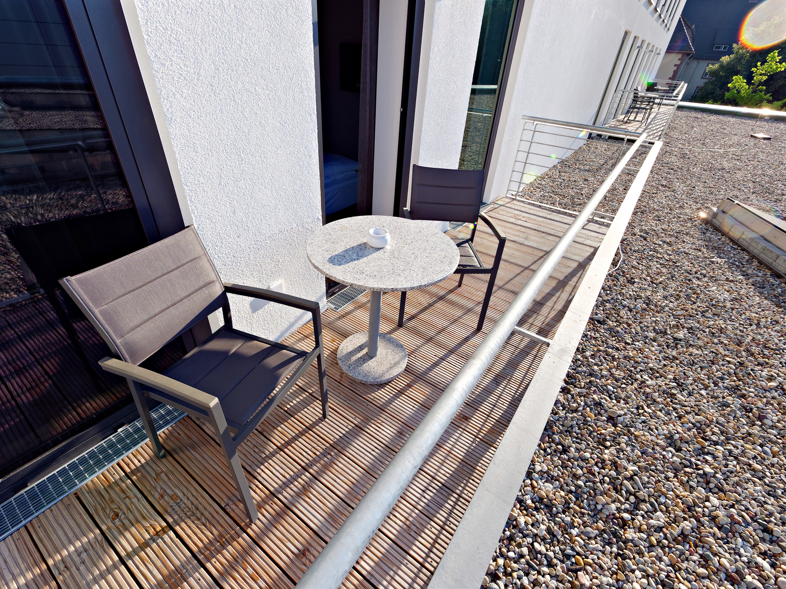 Zwei Stühle an einem runden Tisch auf einem Balkon bei Sonnenschein