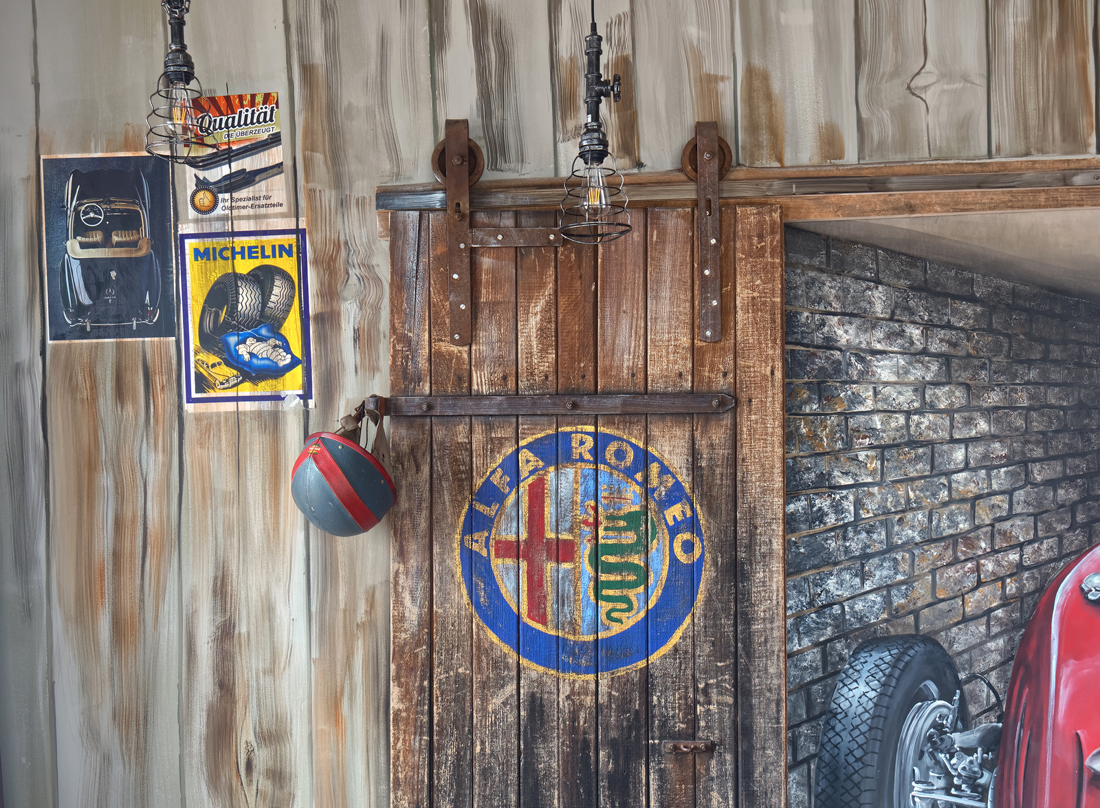 Das Bild zeigt eine Holztür mit dem Alfa Romeo Logo in der Mitte. Daneben hängen Werbeplakate und ein Helm. Die Wand ist mit Holzbrettern verkleidet und hat einen rauen, industriellen Look. Im Hintergrund ist ein Teil eines Oldtimers und eine Ziegelwand sichtbar.