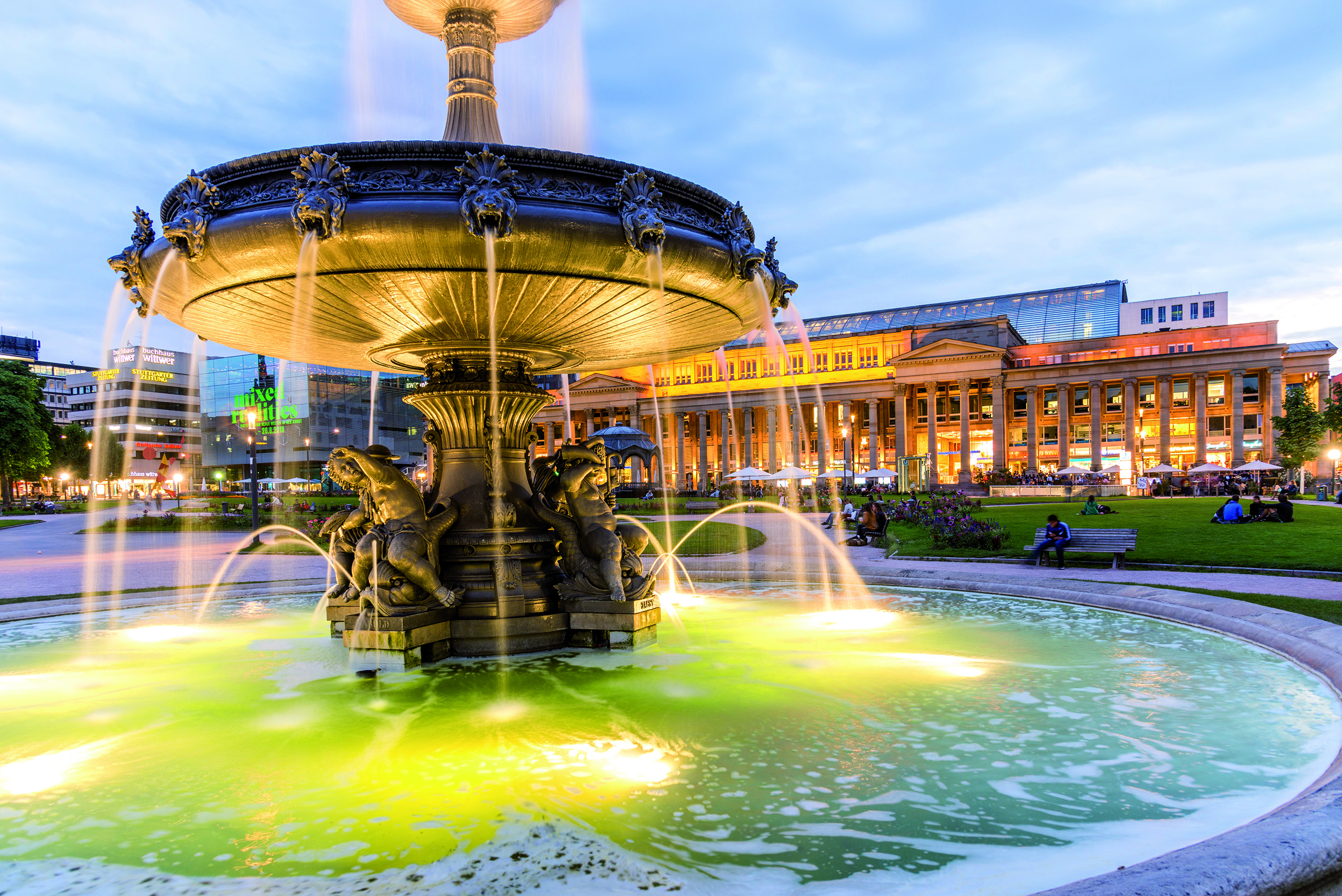 Beleuchteter Brunnen auf dem Stuttgarter Schlossplatz bei Dämmerung.