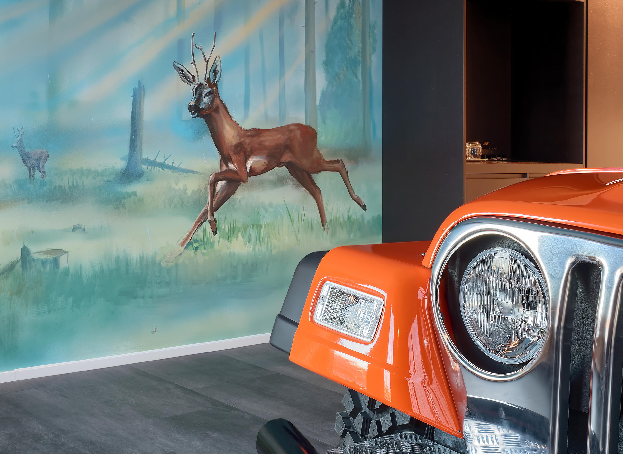 Detailaufnahme des orangefarbenen Autobetts vor einer bemalten Wand, die eine Waldlandschaft zeigt